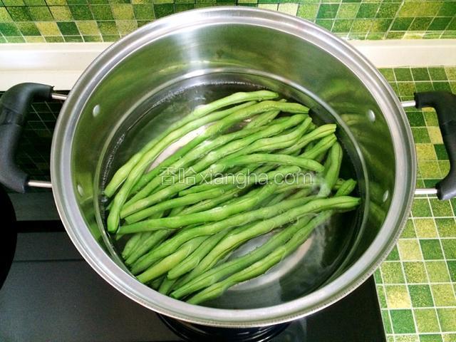 锅中坐水，水开后放入四季豆焯熟；