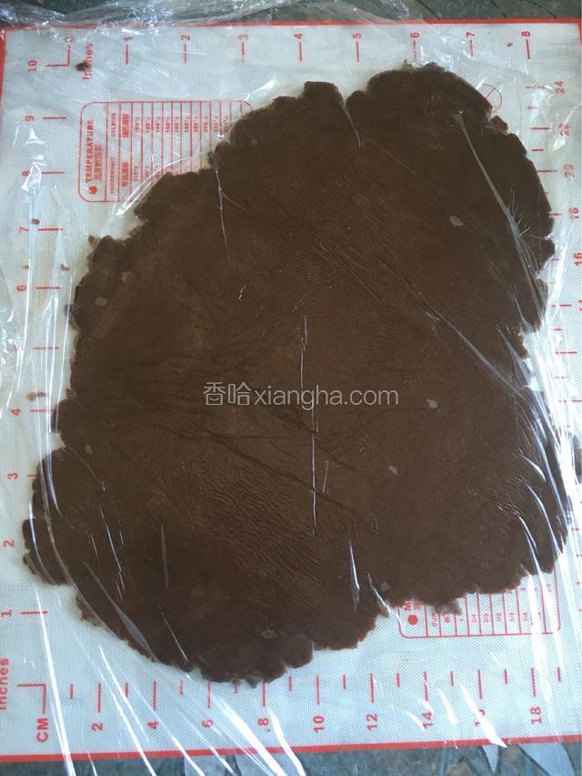 将可可面团铺在不粘布上 上面放上一层保鲜膜 用擀面杖擀成厚度大约3mm的大片
