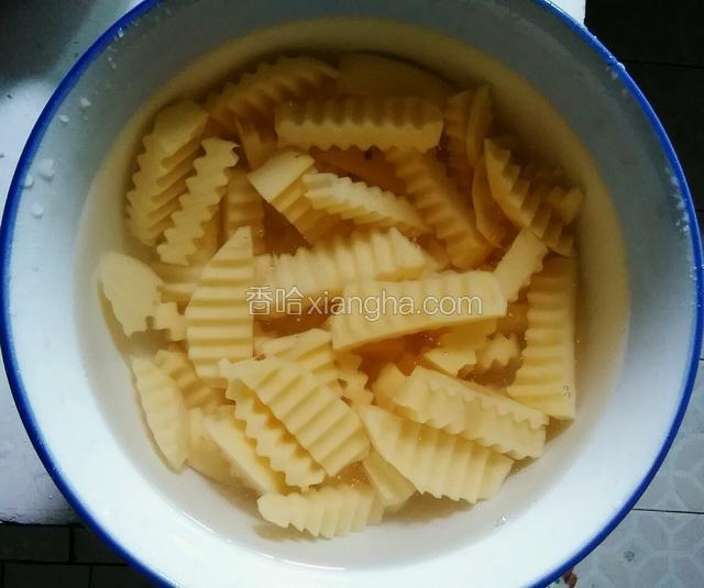然后将土豆用波浪齿形的刀，切成一条一条的，放入水中清洗 