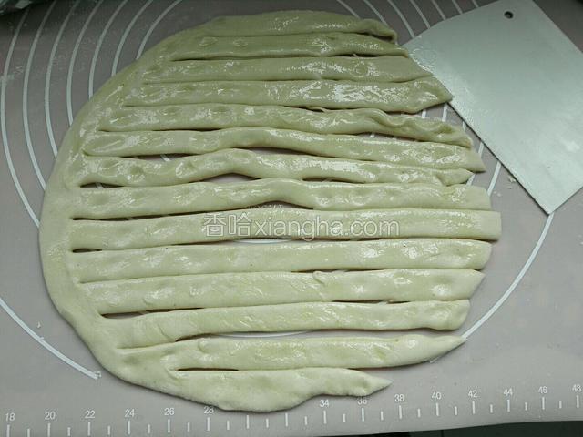 松弛好面团不用揉，直接放面板上擀成圆饼，用毛刷抹一层油，然后用切刀切岀数条，一边不要切段。
