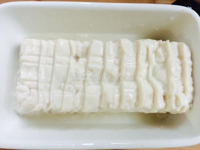 把内酯豆腐去掉外包装倒在深一点的盘子中，把豆腐用刀划成一片一片的。