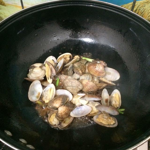 这时候加入适量味极鲜酱油再翻炒几下，看到花蛤全部开口马上关火。