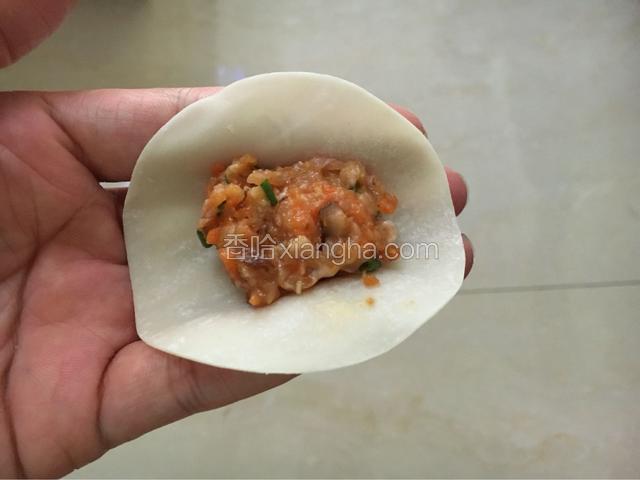 准备好饺子皮开始包饺子了（饺子皮是买现成的）再准备一小碗清水。
取一块饺子皮，中间放好馅料，尽量让馅居中，（如果饺子皮太干，在四周轻轻抹一圈水，方便粘紧）
