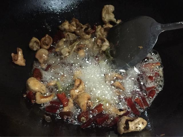 倒入干辣椒、干花椒、姜、蒜、五香粉翻炒香，再倒入肥肠翻炒均匀