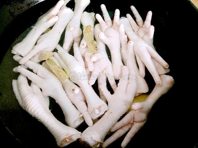锅中烧开水加料酒，姜片下鸡爪焯制15分钟。