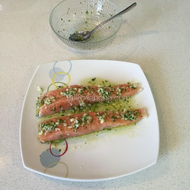 将拌匀的蒜蓉调味料浇在抹好盐的三文鱼上翻动一下让三文鱼的每一面沾上蒜蓉调料汁腌十来分钟再煎也可以直接煎.（为了成品图拍出来效果好看点，所以今天三文鱼去骨了，平时我都是整块煎）