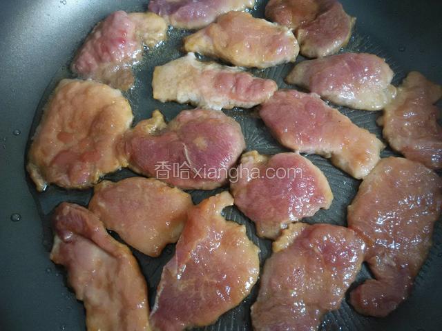 把猪肉片一块块摊进锅里小火煎制。
