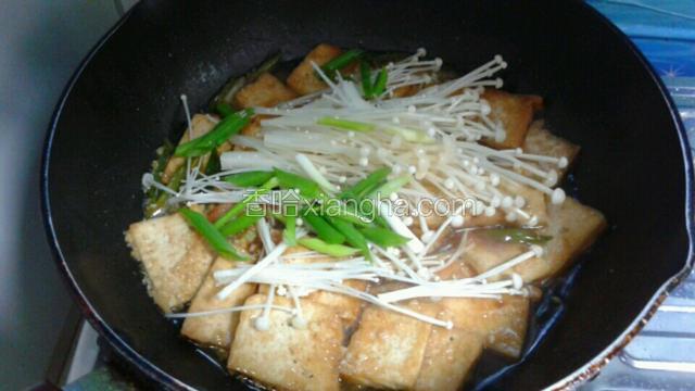 等豆腐入味后，放入金针菇和剩余小葱，翻炒直至收成酱汁关火出锅。
