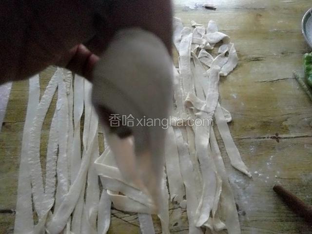 擀好对折，右手钩着中间，左手慢慢伸拉，使得宽面略长略薄一些