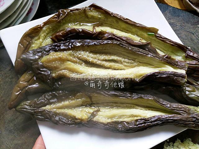 蒸好的茄子表面皱巴巴的就好了，从中间对半剖开一个口子，两头和底部不切断。刚蒸好的茄子内部有热气注意烫手！