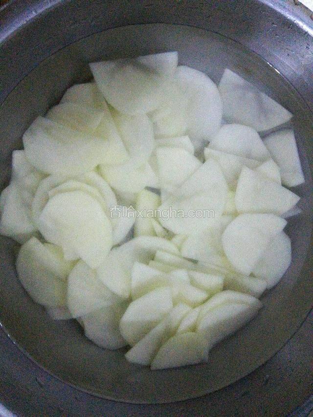土豆一分为二切薄片，放在凉水中浸泡，多换几次水，直到水变清