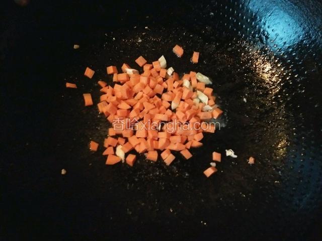 另起油锅，把葱花爆香后，倒入胡萝卜丁，翻炒一分钟左右。
