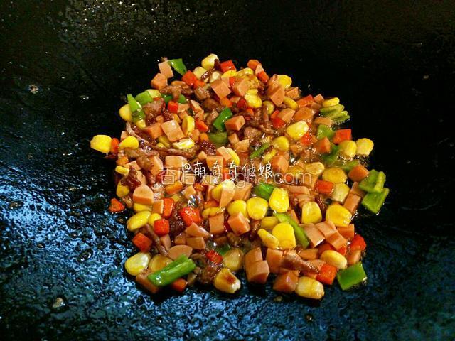 先加玉米粒和胡萝卜丁翻炒片刻，再加火腿丁和青椒丁翻炒片刻。