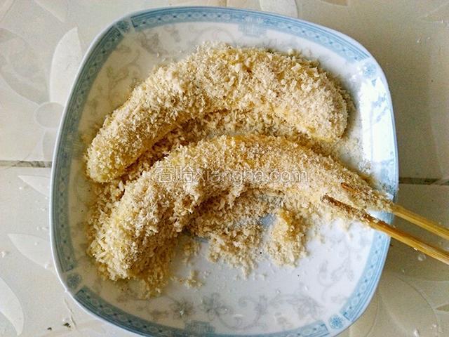 再准备一个干净的盘，倒入面包糠，把图4放入盛面包糠的盘里，均匀的裹上面包糠。