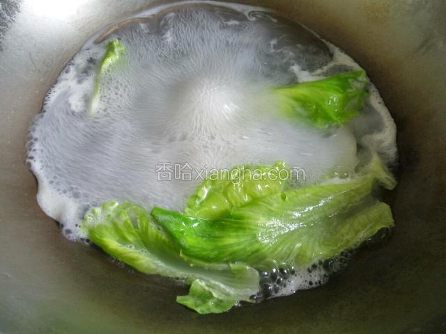 在把生菜放入煮面条的水中焯熟捞起放入碗中