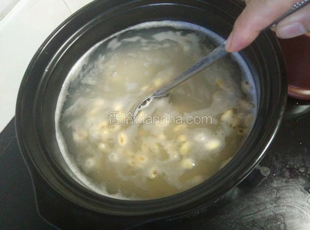 砂锅水烧开，倒入大米和黄豆，用勺子搅动，防止粘锅。