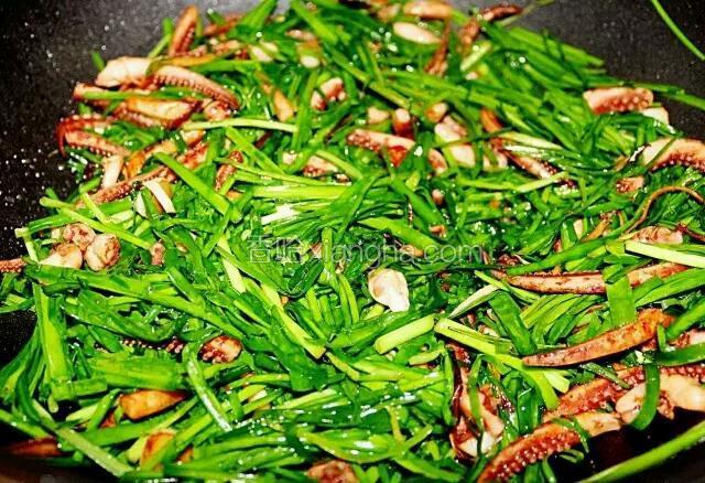 韭菜入锅，翻炒均匀，使得韭菜的菜香融入鱿鱼。