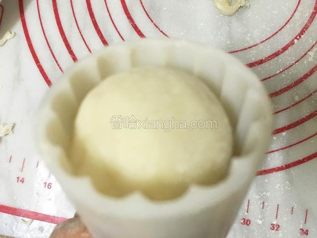 月饼模具也沾一下熟糯米粉，再轻轻的敲出，把冰皮月饼球放入模具中，轻轻的往下按压即可脱模。