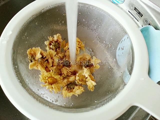 菊花放在漏勺内，在流动的水中冲洗干净