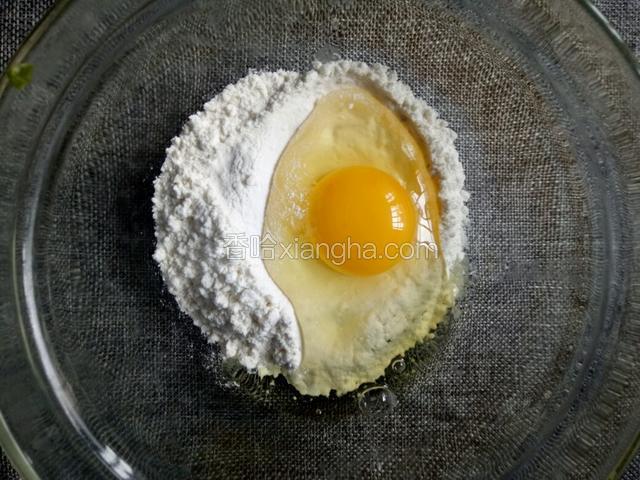 面粉放入碗中，磕入一个鸡蛋。
