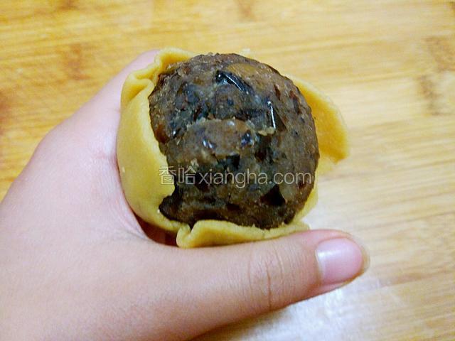 将芸豆馅儿放入面皮中，用虎口包成圆形。