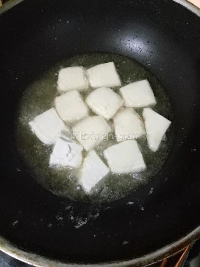 锅中注入适量玉米油，烧至七成热下裹满生粉的豆腐炸制。