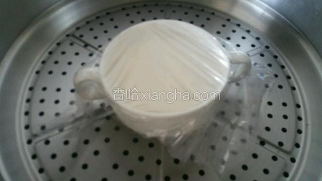 蛋清牛奶从牛奶碗边倒回碗中，奶皮浮起，锅中加入适量水烧开，牛奶碗盖保鲜膜放入锅中