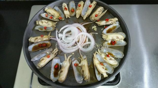 倒点料酒在蛏子上，辣椒撒在蛏子上，把调好的料汁浇在蛏子上