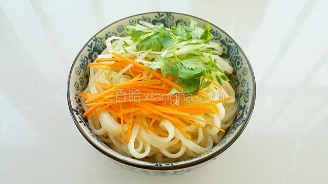 把煮熟的面条放入碗中，上面放上胡萝卜、黄瓜和香菜。