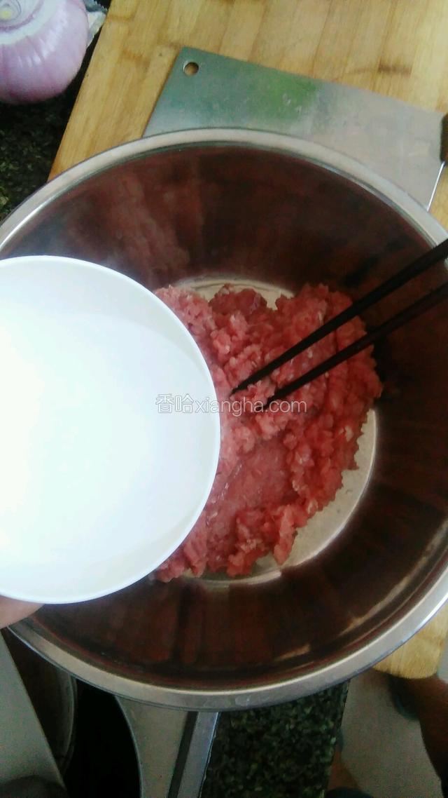 准备半碗水慢慢的倒入牛肉中，边倒边用筷子顺时针搅动，直到牛肉把水完全吸收。