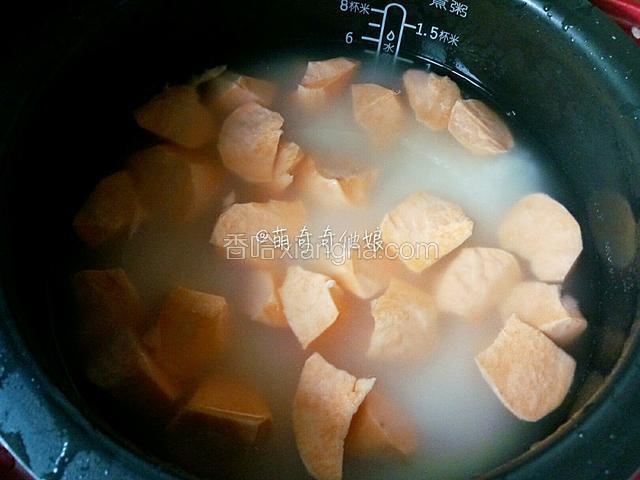 把浸泡米的水倒掉，重新注入干净的水。水量根据米量决定，我家球釜电饭煲上有刻度，几杯米对应几刻度，非常方便。
一般来说米和水的比例是1：1.2-1.5。根据个人喜欢的软硬程度增减。
红薯削皮后切滚刀或大块。我家向来用最老式的办法就是左手拿红薯，右手拿菜刀斩，边斩边转动红薯，就成了如图所示的红薯样子了。