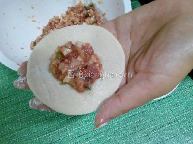 取一张饺子皮，放适量拌好的肉馅在中间（饺子皮边边都沾点水）
