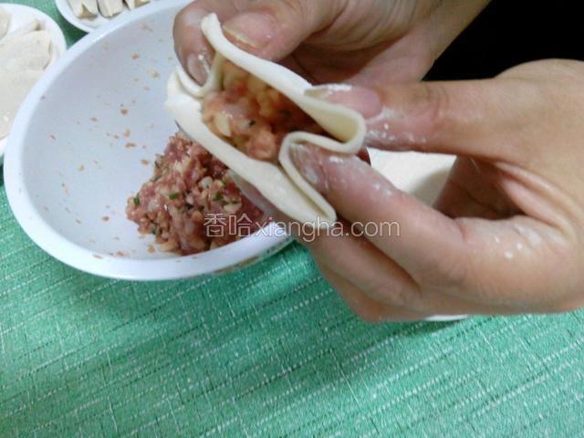 把饺子皮对折，用左右两个手的食指把两边的角压进去