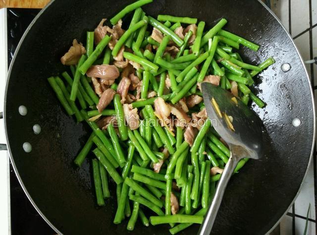 把准备好的豆角倒入锅里，放入少许的盐及生抽，跟肉片一起翻炒片刻