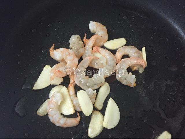 锅烧热下适量油爆香蒜片下虾仁，炒至变色