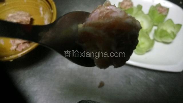 手戴上一次性手套，把肉馅挤成丸子放在青菜心中。