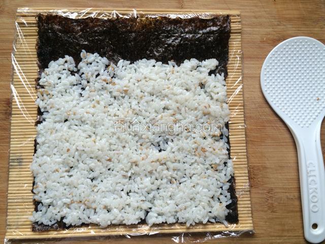 
将拌好的米饭铺在海苔上，用饭铲背面将米饭压实，也可以用手指背压米饭，最上边留两厘米不铺米饭