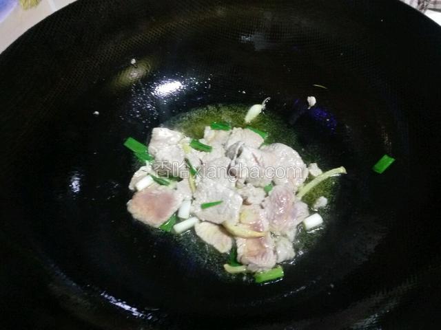 放入肉片炒至断生，然后放入葱花。