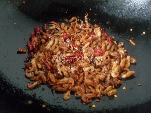 等河虾的水分煸炒干后，再转小火慢慢煸炒，把辣椒的香味炒出来，小河虾炒出来发出沙沙响的声音就可以了。