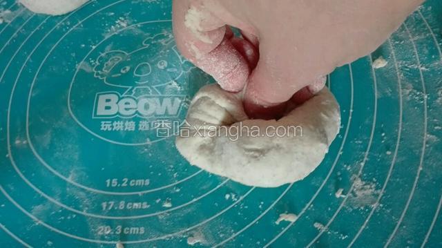 取出一个小面团，用大拇指按其他手指负责往里抓面，然后倒扣，整理成圆形