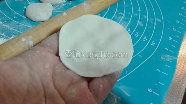  取出一个小圆饼，用擀面杖把圆饼擀成面片儿。