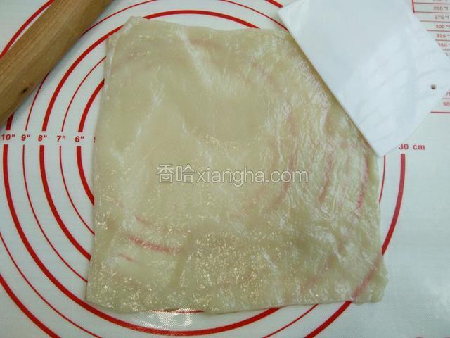 擀好后，拿走保鲜膜，用刮板切去边缘不均匀的地方
