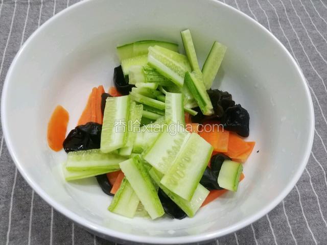 将黄瓜也放进盛胡萝卜和木耳的容器里。
