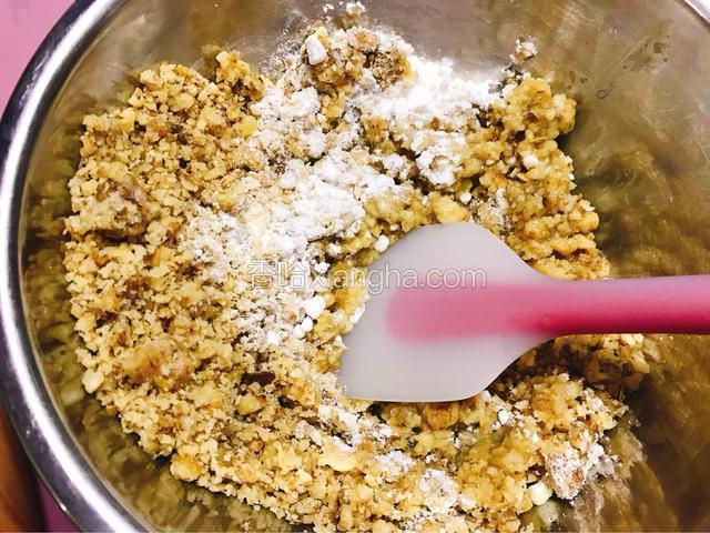 核桃和黄油倒入装有糖粉炼乳的盆内。用刮刀搅拌均匀。