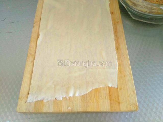 拿一张干豆腐铺在菜板上。
