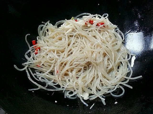 接着把苕粉倒入锅内，快速用炒勺不停翻炒一分钟