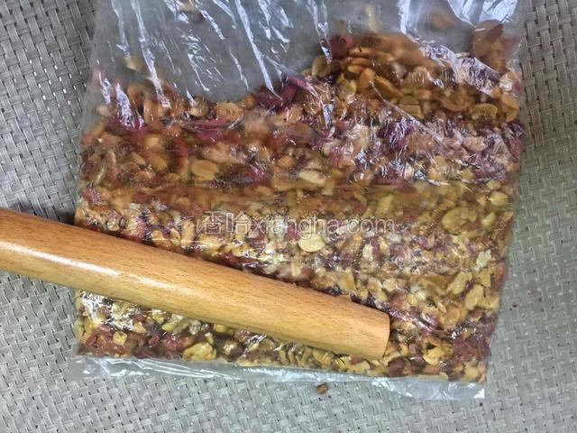 用擀面杖压碎花生。