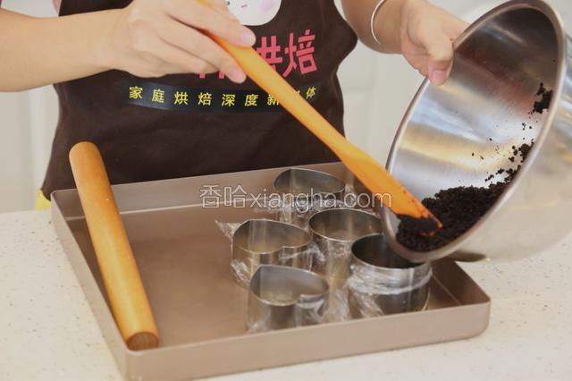 4.用保鲜膜包住慕斯圈的底部后，加入饼干碎
