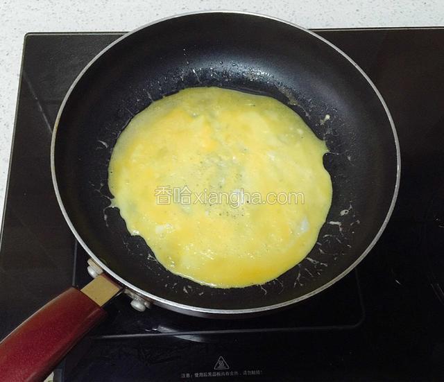 用汤勺倒入鸡蛋液。（如果锅不热，蛋液不易均匀摊开在锅底，可能会往两边流。我的方法是：中火倒入蛋液摊开成形，转小火慢煎。）