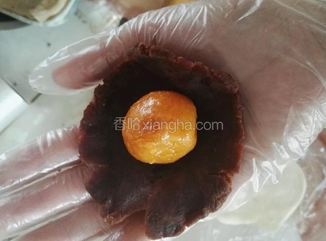 取一份红豆沙，按扁放入鸭蛋黄包好备用